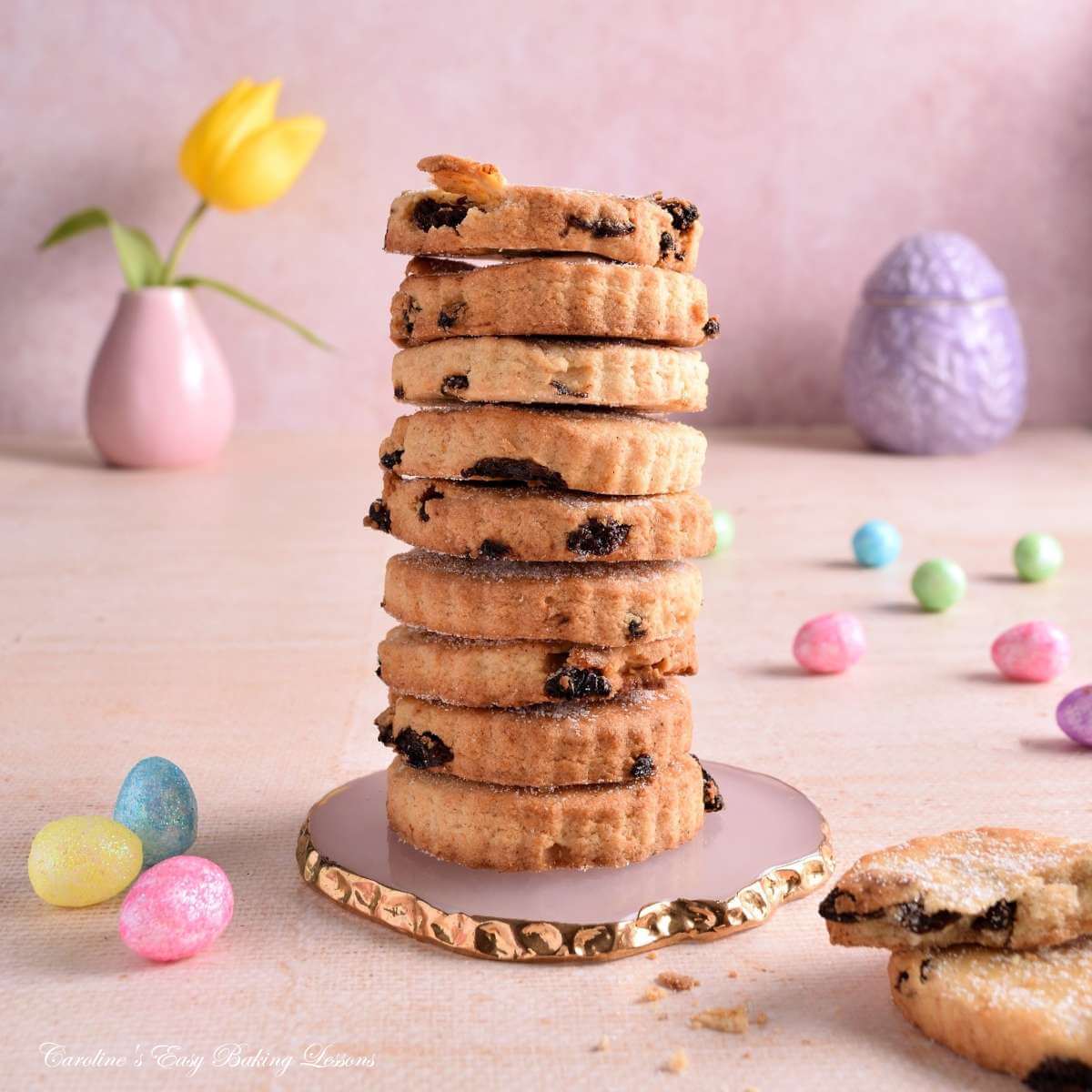 Image of a tall stack of Easter biscuits/cookies, with Easter pastel coloured mini eggs & decorations.