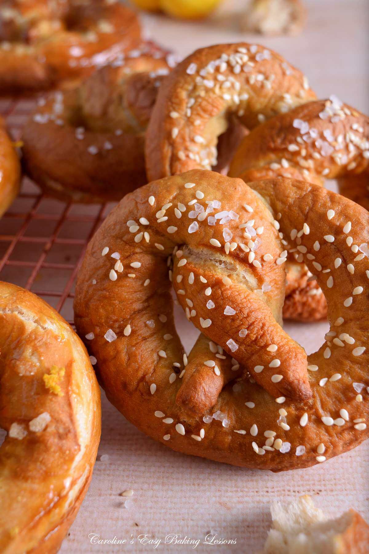 Vertical image very close up of a partial yeast pretzel, showing the texture, sessame seeds and salt.