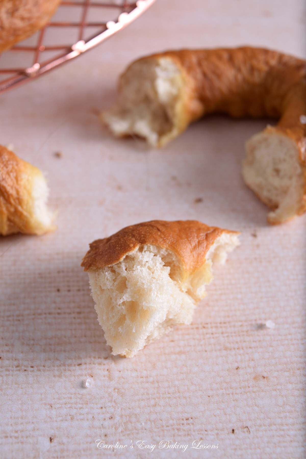 Image showing the texture of a piece of savoury pretzel, with more in the background.