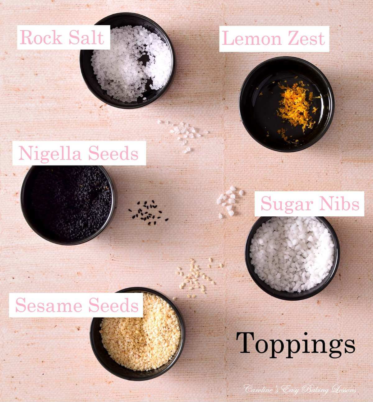 Overhead close image of small black pinch bowls, labelled for toppings on sweet & savoury pretzels.