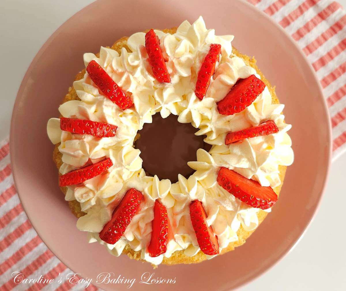 Overhead image of strawberry slices on top of piped whipped cream on a base layer of a bundt cake.