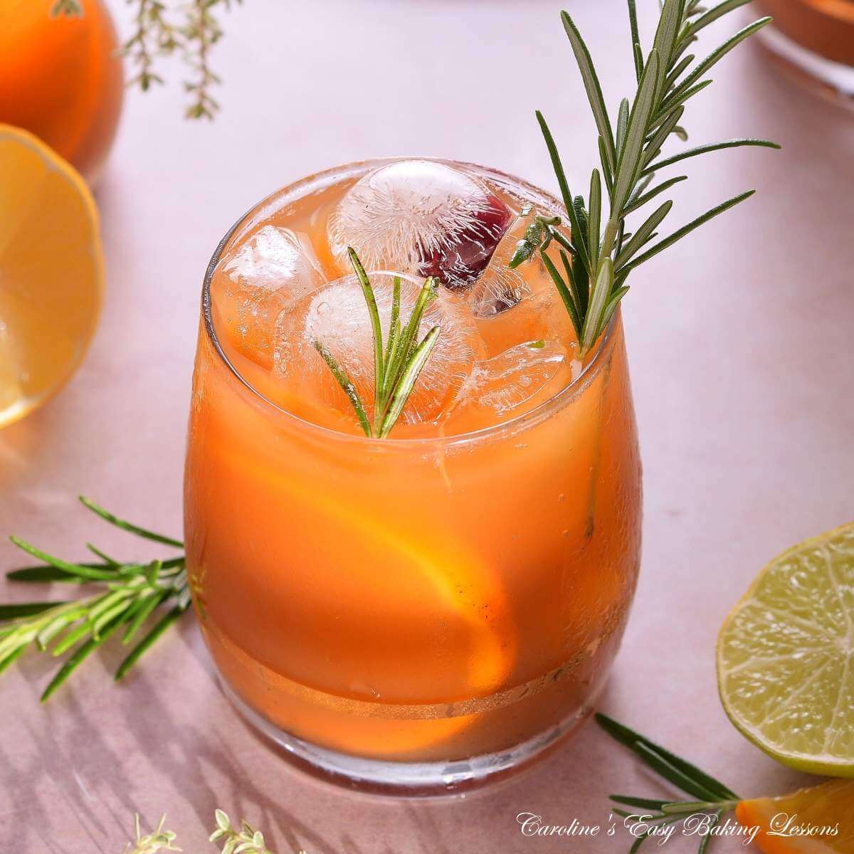 Square close square image at 45 degrees of a bright citrus iced tea in glass, with lots of ice, rosemary garnish and sunny shadows.
