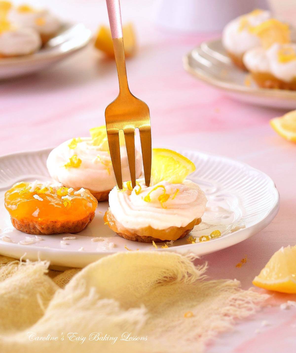 Close image with white, yellow and pink colours, of 3 mini lemon coconut no-bakes bites, with gold fork above coming down.