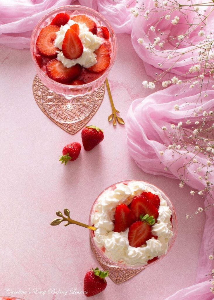 Overhead image on pink backdrop with pink fabric surrounding 2 cocktail glasses with mousse, cream and strawberries.